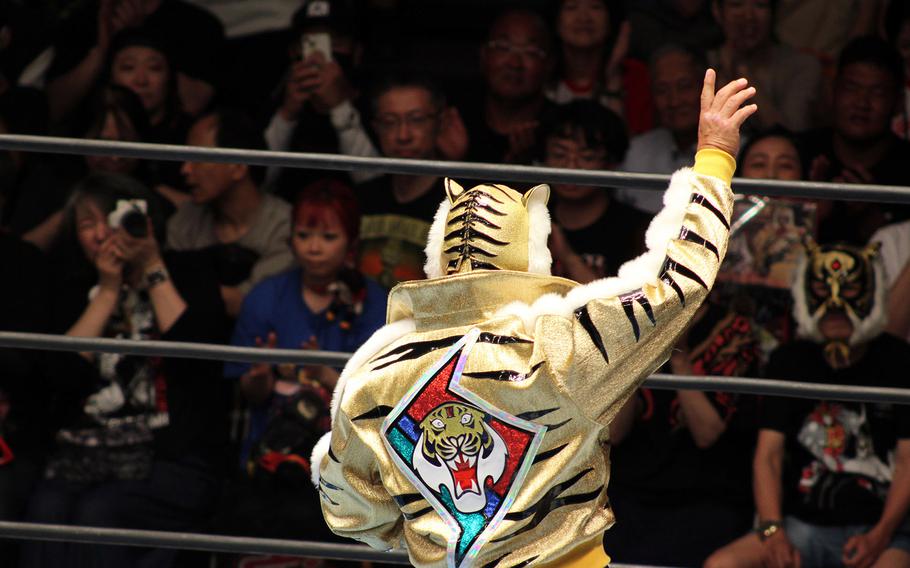 A festively dressed wrestler gestures to the crowd.