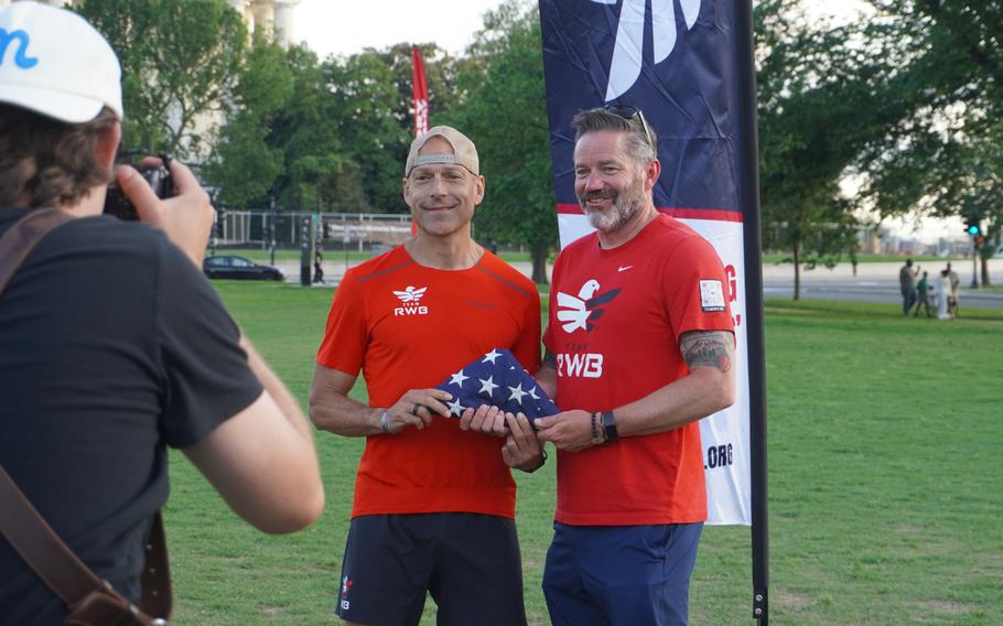 Two men hold a folded American flag