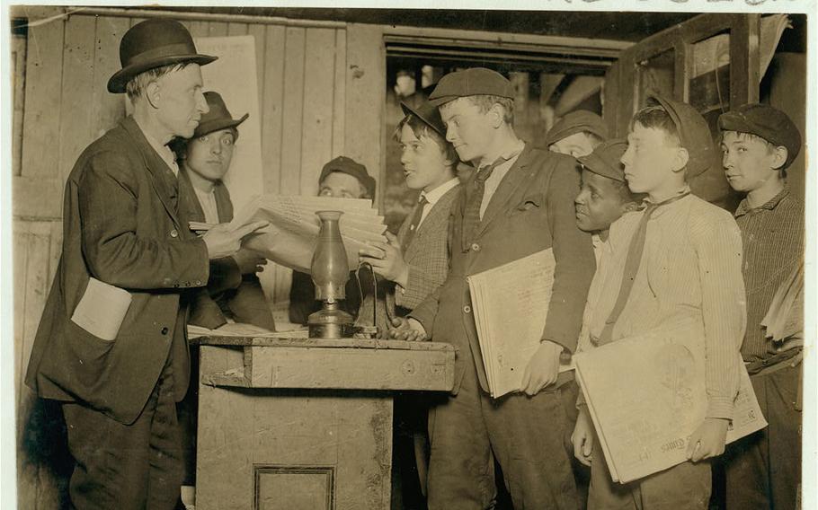 Young boys pick up newspapers to sell in the pre-dawn hours in St. Louis in 1910.