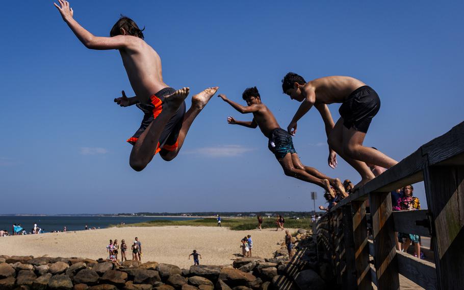 People jump off a bridge into the water at Martha’s Vineyard.