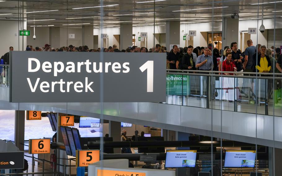 Travelers wait in long lines to check in and board flights at Amsterdam’s Schiphol Airport, Netherlands, Tuesday, June 21, 2022.