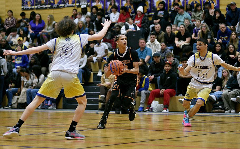 Spangdahlem's Cameron Lewis picks up the ball between Wiesbaden defenders Amare Braxton, left, and Yadier Viera on Jan. 19, 2024, at Wiesbaden High School in Wiesbaden, Germany.