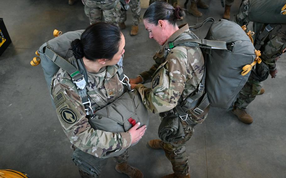 Maj. Talisa Dauz (left) and Sgt. Maj. Jennifer McAlluliffe (right), XVIII Airborne Corps, help each other get rigged up for an all-female airborne jump in honor of International Women's Day, March 13, 2023. The all-female jump is an annual tradition for many Army units.