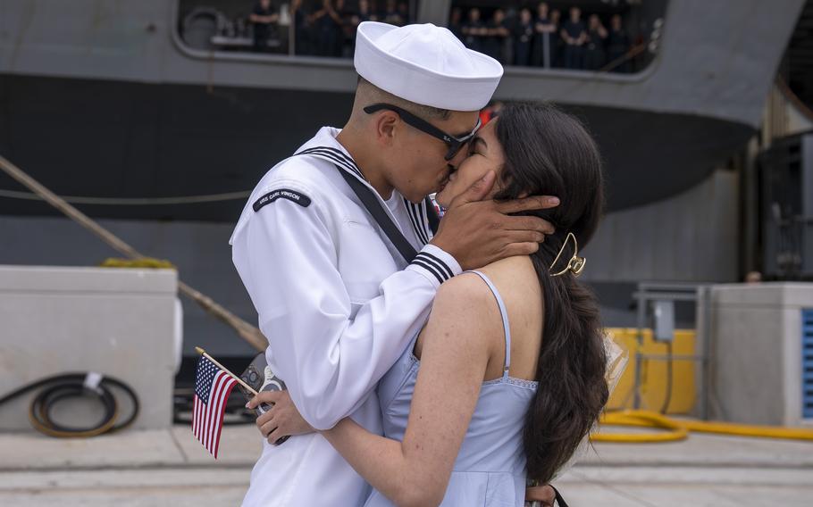 A sailor and a woman share a kiss.