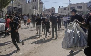 People running along a dirt street and gathering belongings as their homes are destroyed in a refugee camp in the West Bank.