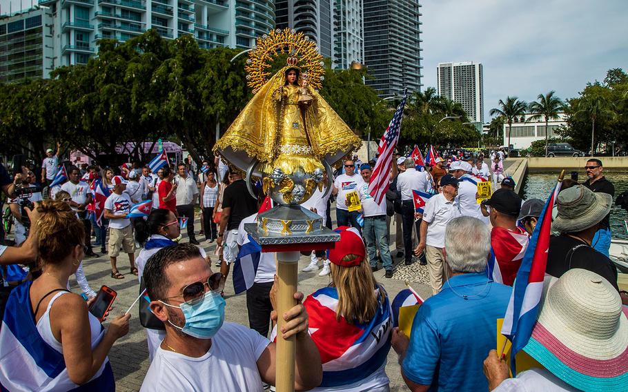 Rey Acosta holds an image of ìOur Lady of Charity (Virgen de la Caridad del Cobre)  during a gathering by Cuban exiles at the Museum Park after a car caravan organized by the Assembly of the Cuban Resistance through the streets of Miami from the Cuban Memorial in Tamiami Park to the Freedom Tower in Downtown Miami.