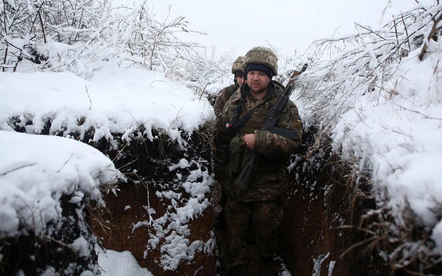 Ukrainian service members walk in a trench on their position on the front line with Russia-backed separatists near the small town of Svitlodarsk, in Donetsk region, on Dec. 18, 2021. 