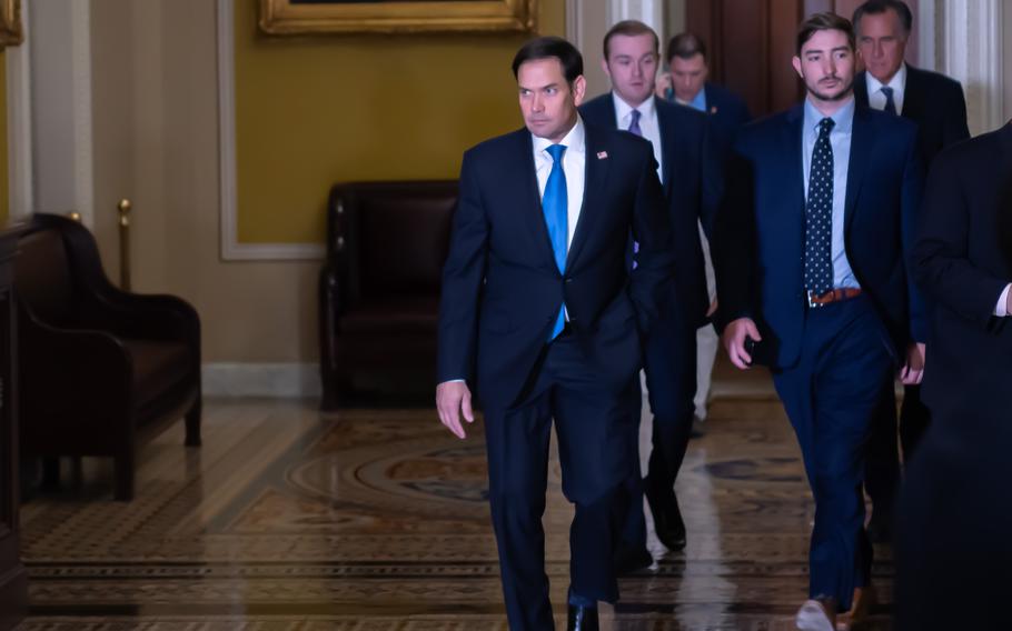 Marco Rubio seen walking with a suit and a blue tie.