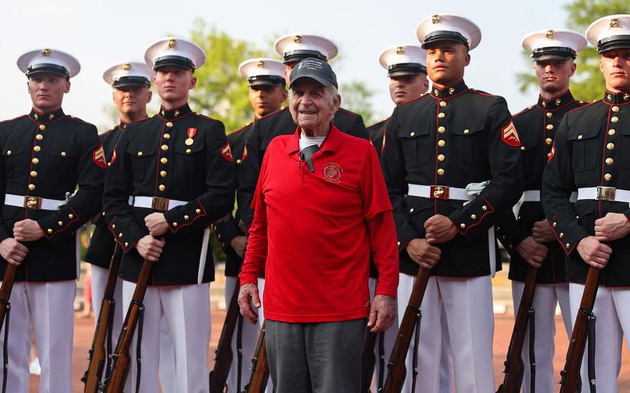 A veteran in a bright red shirt stands out among active duty marines in uniform.