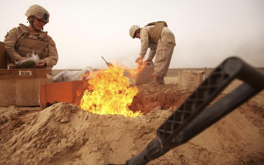 In this 2012 photo, Lance Cpl. Nathanial Fink, left, and Lance Cpl. Garrett Camacho burn trash in Afghanistan. The military used the open-air pits to dispose of unwanted items, including chemicals, human waste, medical items and food leftovers. 