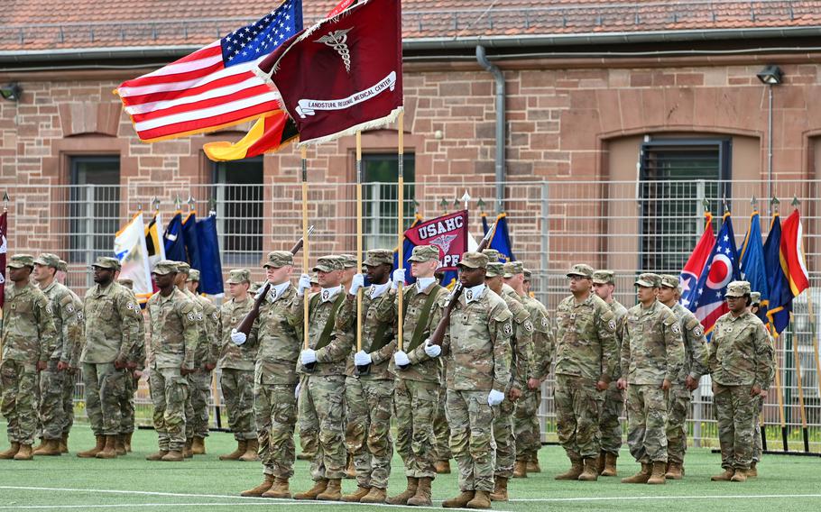 Soldiers stand in formation below the U.S. flag and Landstuhl Regional Medical Center flag.