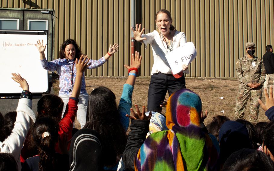 Volunteer teacher Morgan Guinn, center, leads an English language class for Afghan refugee children at Rhine Ordnance Barracks in Kaiserslautern, Germany, Sept. 23, 2021, with help from Tammy Cortez-Janes, back left. Around 5,400 people who fled Afghanistan after the Taliban took control of the country in August are housed at ROB until flights to the U.S. resume.