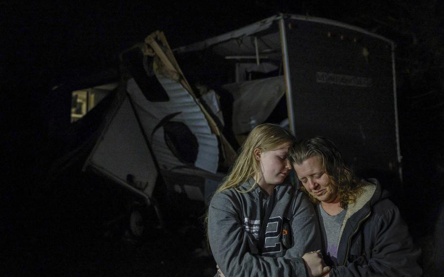 Brittaney Deaton, 17, left, comforts her mother Amber Zeleny, 53, while speaking with reporters after a severe storm passed in Johnson County near Burleson, Texas, Tuesday, April 5, 2022.  The latest round of storms to pound the South prompted a flurry of tornado warnings at the start of what forecasters said could be two days of violent weather in the region. More than 55,000 homes and businesses were without power Tuesday morning from eastern Texas to southern Mississippi after storms. 