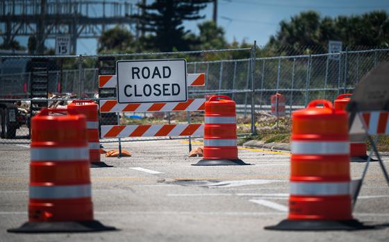 A road lined with traffic barriers and a sign reading “road closed.”