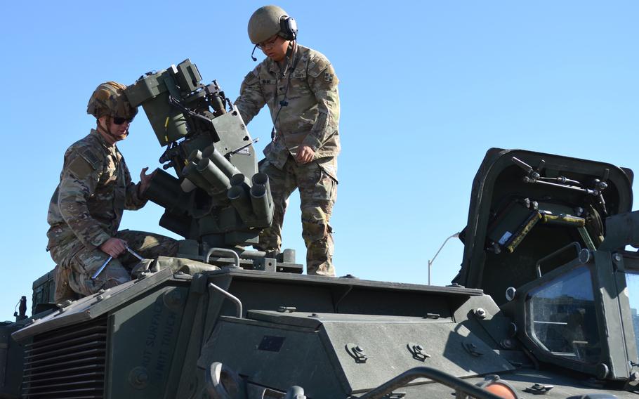 Two soldiers mounting a camera onto a military vehicle. 