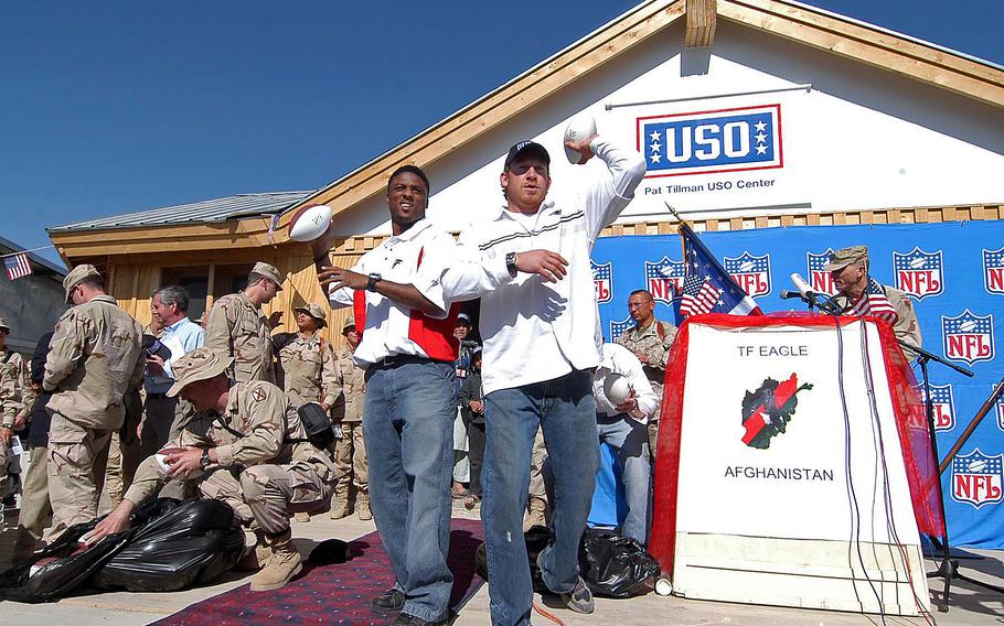 Atlanta Falcon Warrick Dunn, left, and New England Patriot Larry Izzo toss out autographed footballs to the troops before the ribbon-cutting ceremony to open the Pat Tillman USO Center on Bagram Airfield, in April 2005. The center is dedicated to the former NFL player killed in action while serving in Afghanistan in 2004.