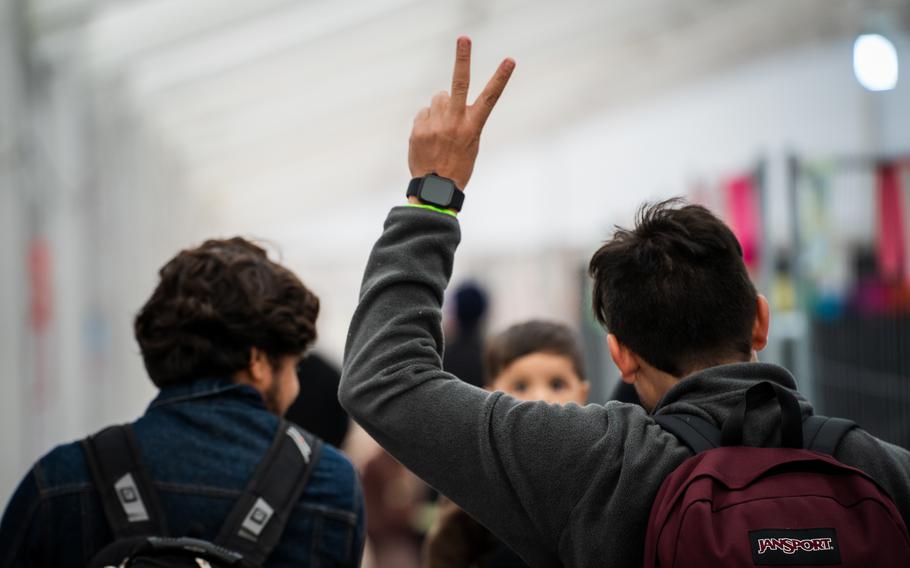 An Afghan evacuee makes a peace or victory sign as he makes his way to a waiting area in a passenger terminal at Ramstein Air Base, Germany, before traveling to the United States, Oct. 9, 2021.