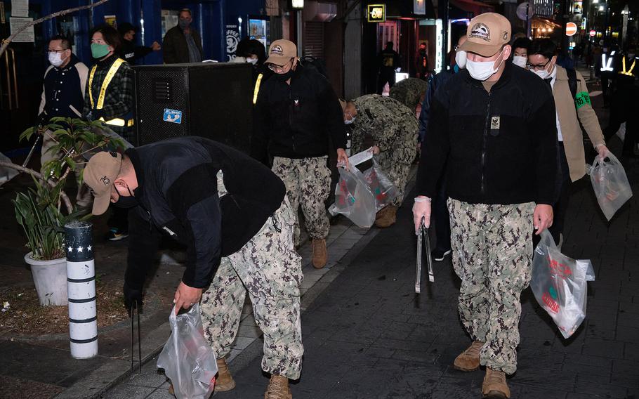 Sailors work with locals to clean up a popular nightlife district known as “The Honch” near Yokosuka Naval Base, Japan, Friday, Nov. 19, 2021.