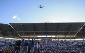 Onlookers in a stadium watch a B-52 fly overhead.