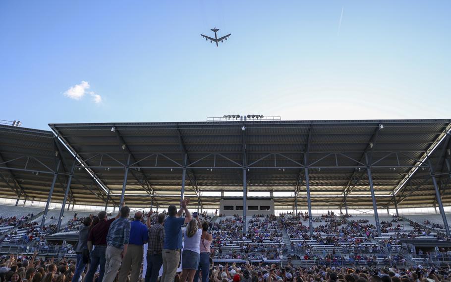 Onlookers in a stadium watch a B-52 fly overhead.