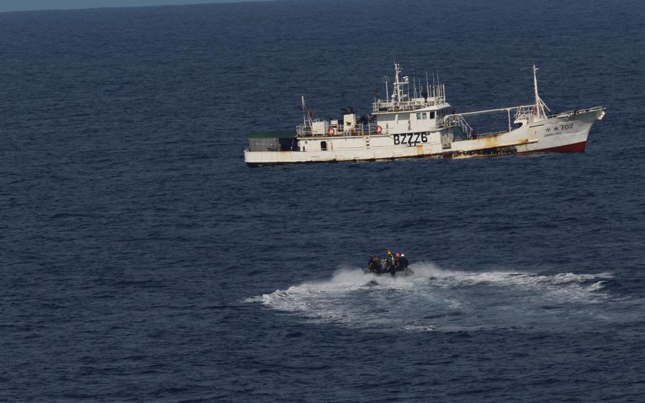 The USS Shiloh sails in the ocean with a small boat