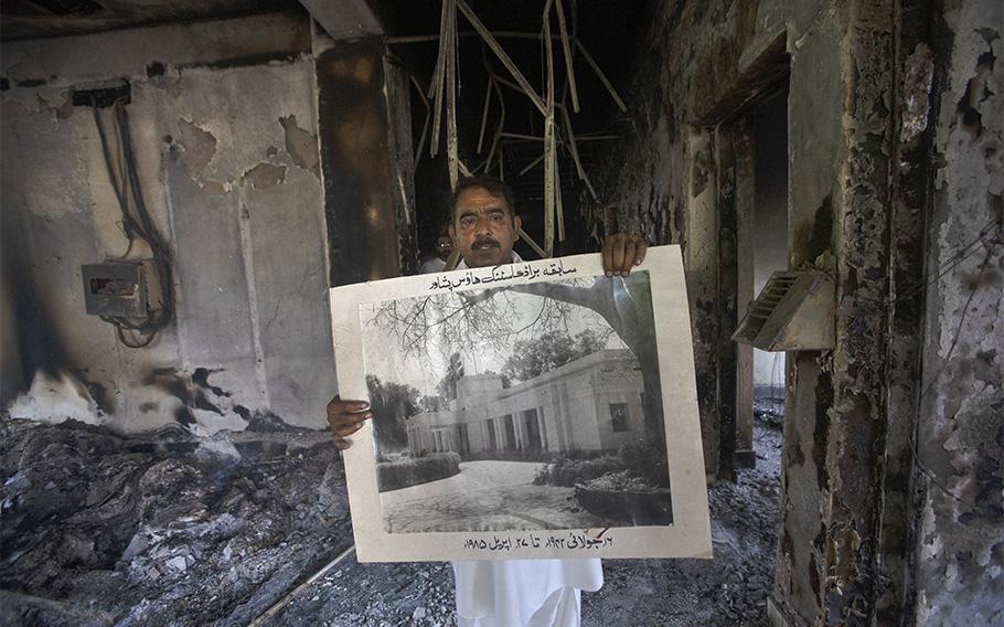 A government employee displays an archive picture inside the Radio Pakistan building that was burnt in clashes between police and the supporters of Pakistan’s former Prime Minister Imran Khan, in Peshawar, Pakistan, on May 11, 2023. 