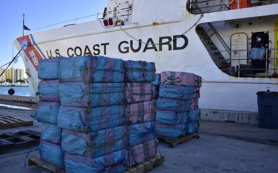 Bales of contraband are stacked in front of the Coast Guard Cutter Dauntless (WMEC-624) at Base Miami Beach, Dec. 7, 2021. The contraband was part of more than $148 million of illegal narcotics offloaded by the Dauntless crew.