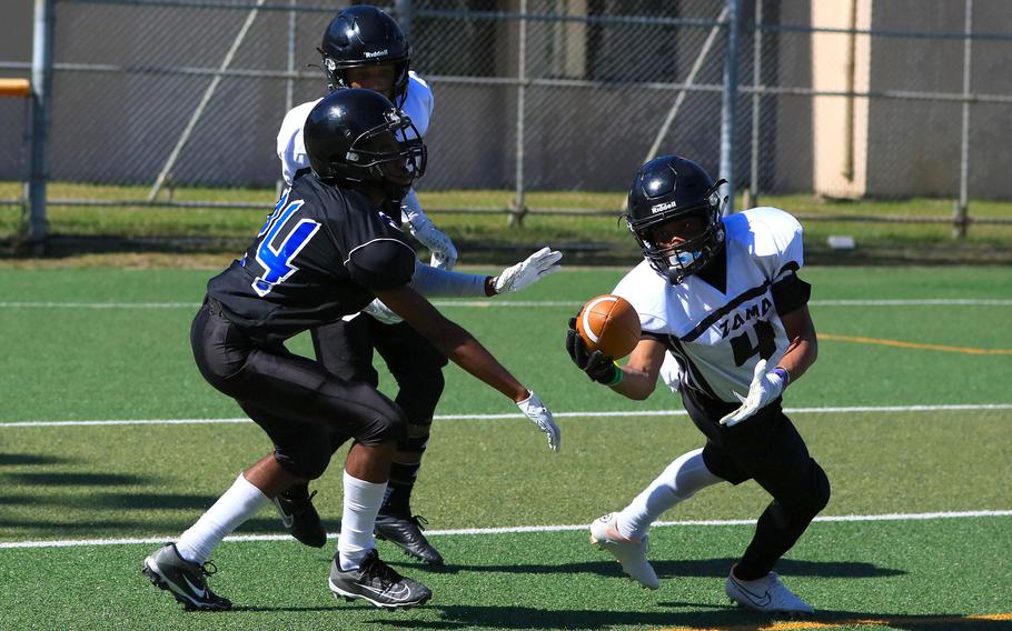 Zama's Ayden Helton snags an interception in front of Osan's Jamaryeon Price.