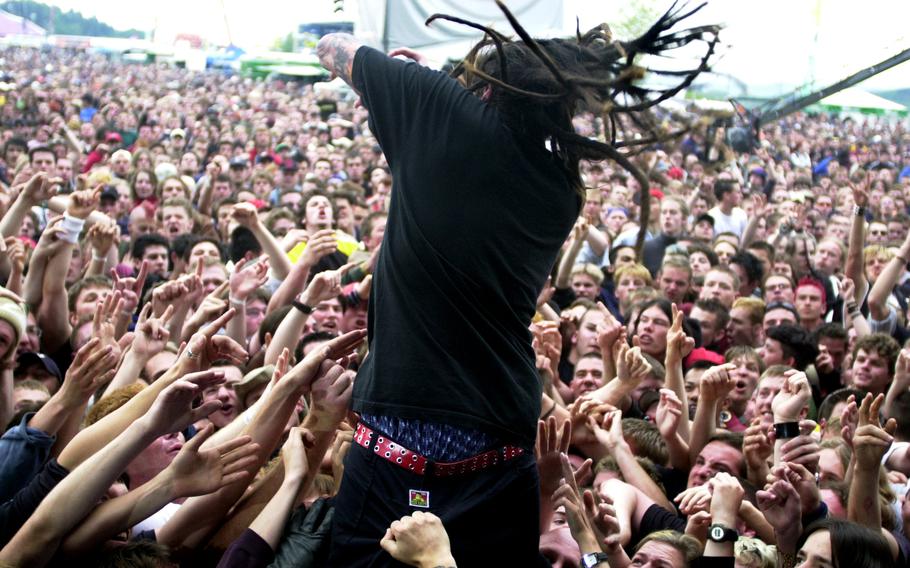 A man, seen from behind, jumps into a crowd of outstretched hands.