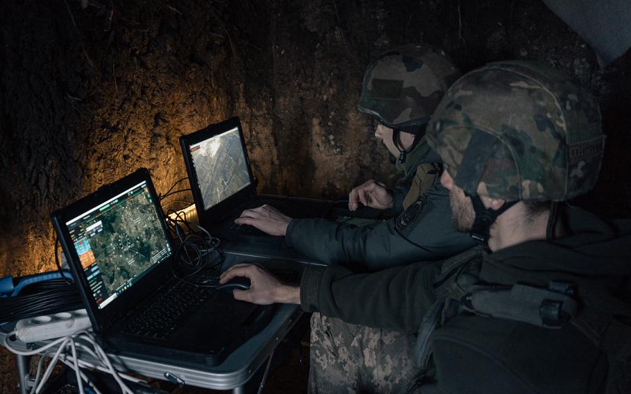 Ulysses and another soldier monitor footage from a reconnaissance drone from devices set up in a foxhole.