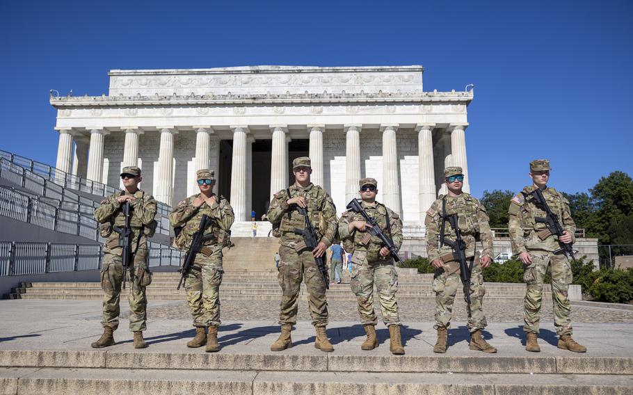 Six armed soldiers stand on  steps near the Lincoln Memorial.