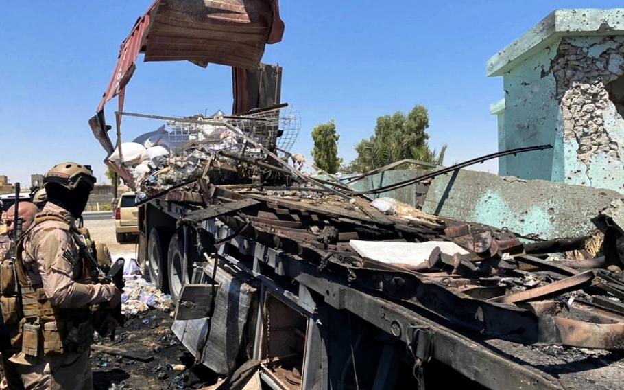 Security forces gather near a destroyed truck used as rocket launcher that sits near a damaged mosque in Anbar, Iraq, Thursday, July 8, 2021. Rockets targeted the heavily fortified Green Zone in the Iraqi capital Baghdad on Thursday, causing some damage but no reported casualties, Iraqi security forces said.