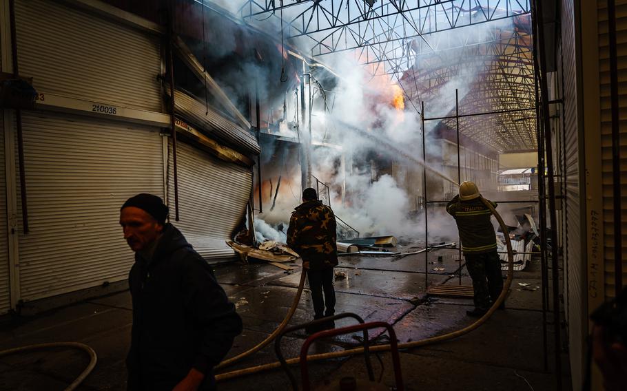 Firefighters put out flames caused by a Russian bombardment that struck the Barabashovo market in Kharkiv, Ukraine, on Friday, March 25, 2022.