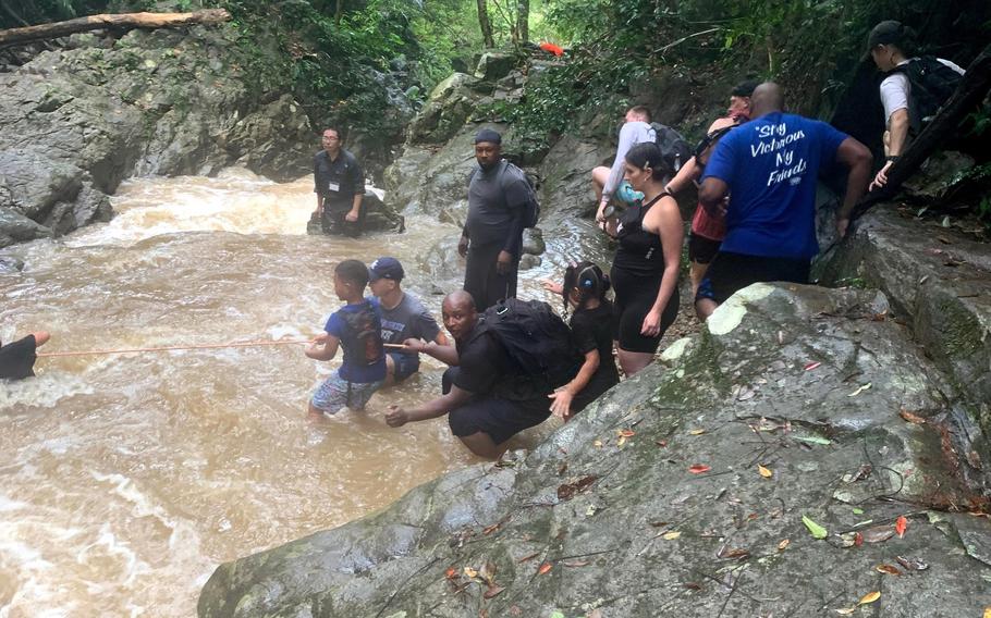 U.S. service members and their families help one another across a raging river during a flash flood at Ta-Taki Falls, Okinawa, Sept. 13, 2020. 