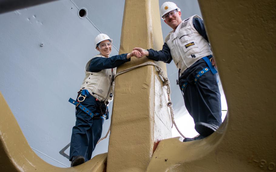 Command Senior Chief Petty Officer Brianna Ridlon and Lt. Cmdr. Jesse Crider pose atop one of the USS Ronald Reagan's anchors at Yokosuka Naval Base, Japan, April 1, 2024.