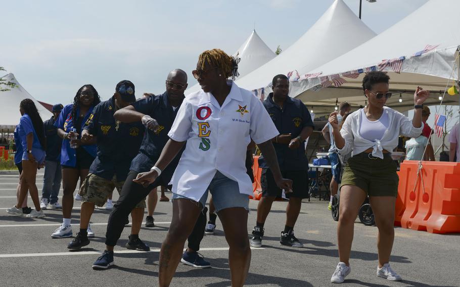 Festivalgoers do a line dance outside.