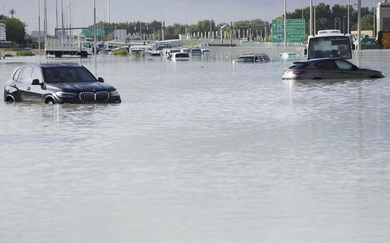 Vehicles sit abandoned in floodwater covering a major road in Dubai on April 17, 2024.