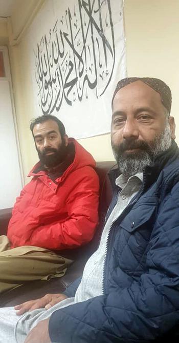 Safi Rauf, left, and his brother Anis Khalil sit under an Islamic Emirate flag in a photo shared after their release from captivity from the Taliban. A months-long campaign by the Biden administration led to their release after 105 days, the State Department said in April.