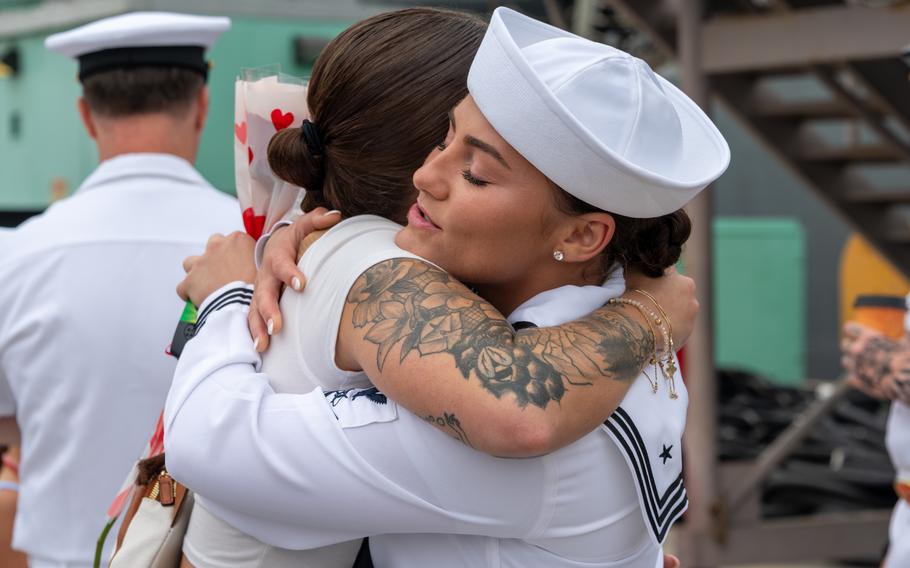A female sailor embraces a woman.
