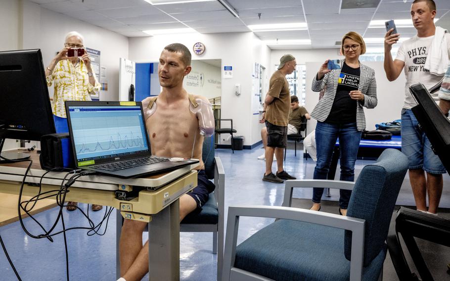 Ilia Mykhalchuk, seated, tests his ability to use his remaining muscles to power prosthetic arms. 