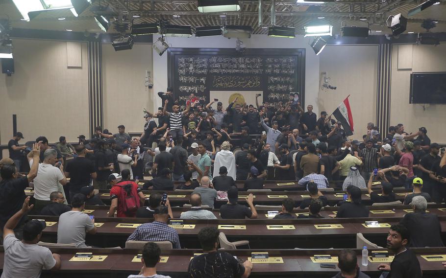 Iraqi protesters pose with national flags inside the Parliament building in Baghdad, Iraq, Sunday, July 31, 2022.
