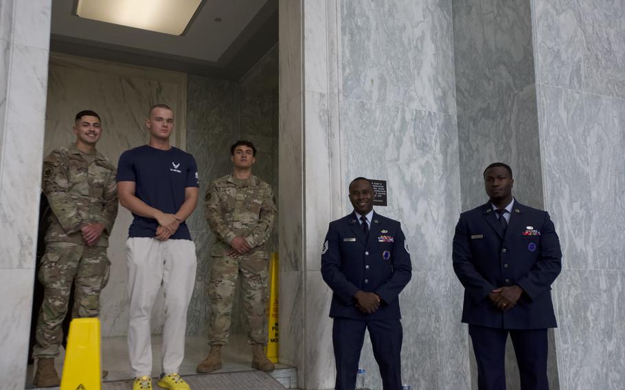 Two Airmen in fatigues and one with his signing in shit, left, and two Airmen in uniform on the right.