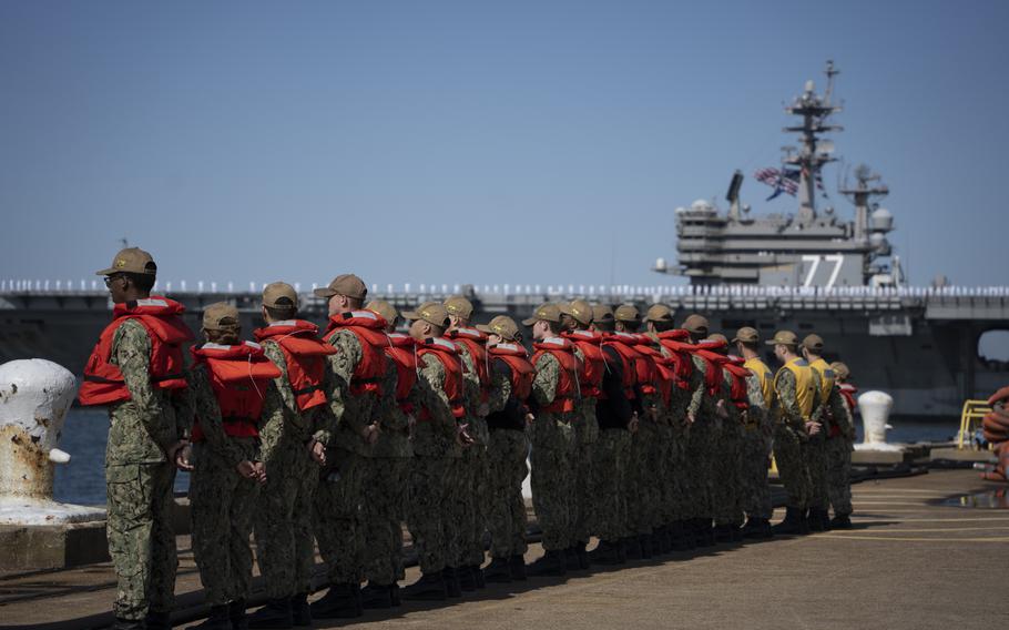 Sailors assigned as line-handlers stand by as the USS George H.W. Bush, along with the staff of carrier Strike Group 10, returns to Naval Station Norfolk, Sunday, April 23, 2023. 