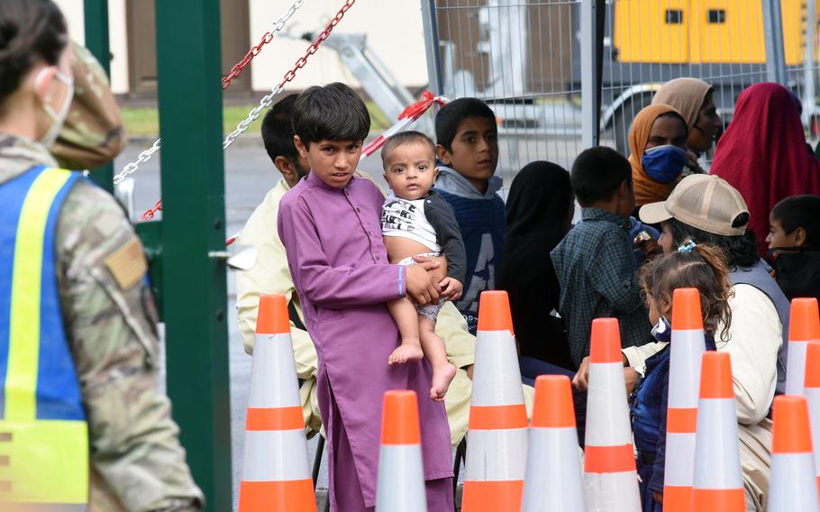 A boy holds a baby while waiting for transit to temporary living facilities with other Afghan evacuees at Ramstein Air Base, Germany, Aug. 23, 2021.