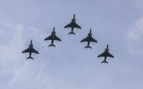 Five AV-8B Harrier II aircraft, seen from below, fly in formation.