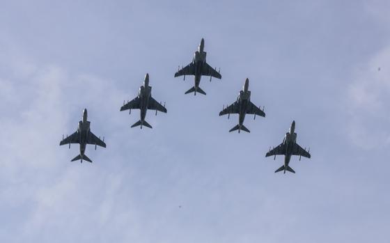 Five AV-8B Harrier II aircraft, seen from below, fly in formation.