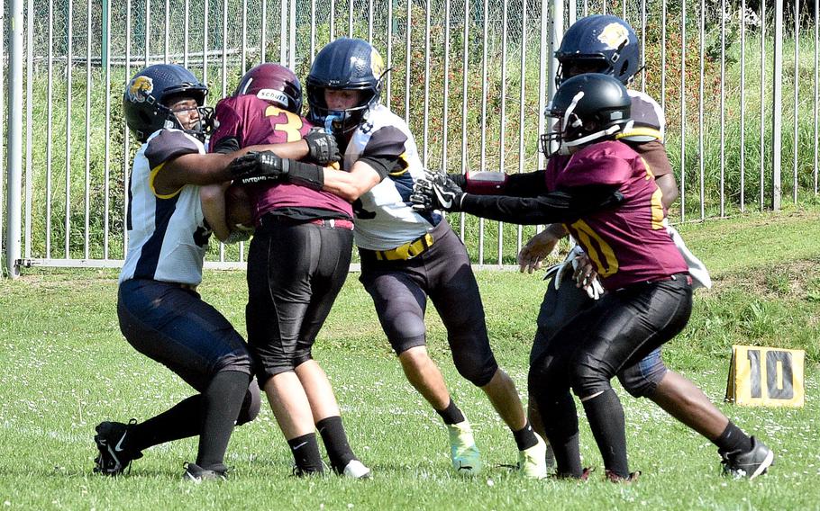 Ansbach defenders, from left, Derek Richard and Nathan Arreguin team up to tackle Buccaneer runner George Corbin during a game on Sept. 16, 2023, at Baumholder Middle High School in Baumholder, Germany.