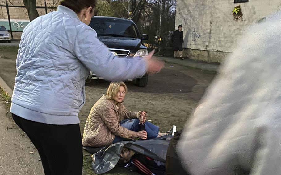 A Ukrainian woman holds the hand of her recently deceased husband.