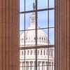 The U.S. Capitol dome seen through a window of another building.