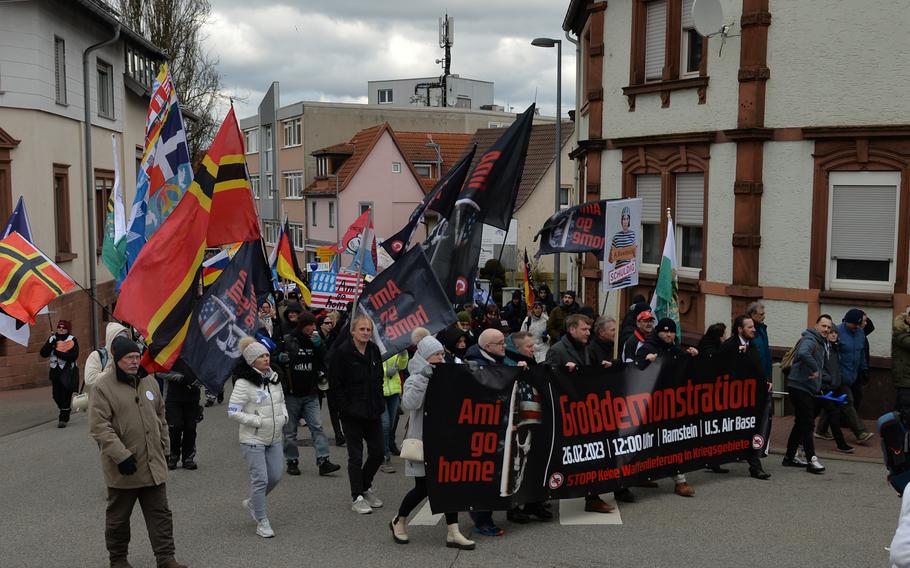 Protesters march through downtown Ramstein-Miesebach, Germany, on Feb. 26, 2023. Banners demand "Ami, Go Home!" using an often derogatory short word for Americans.